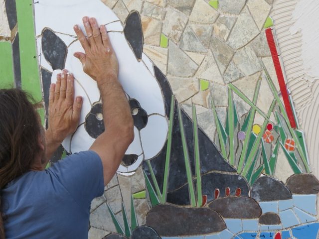Juan piecing mosaic mural of panda